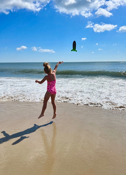 Child throwing toy in surf